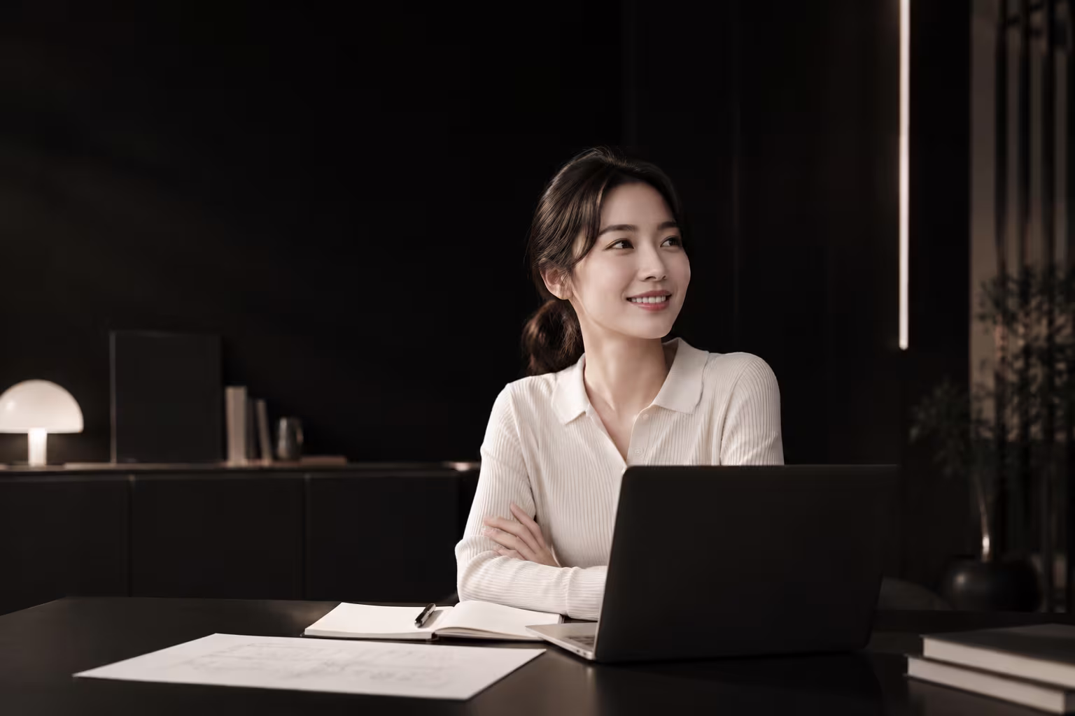 노트북 앞에서 옅게 웃으며 창밖을 보는 사람